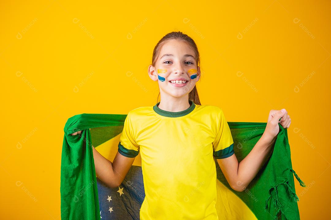 pequena garota caucasiana com bandeira do brasil em fundo amarelo. apoiador de criança brasileira