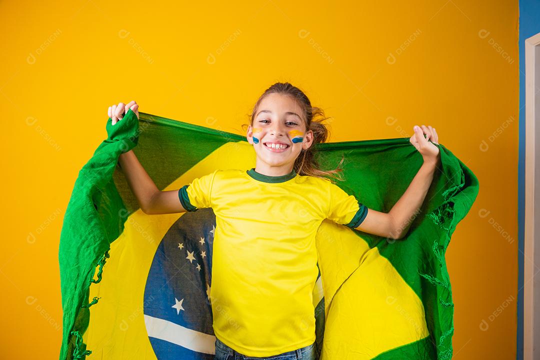 Torcedor de futebol, seleção brasileira. Linda garotinha torcendo por seu time em fundo amarelo