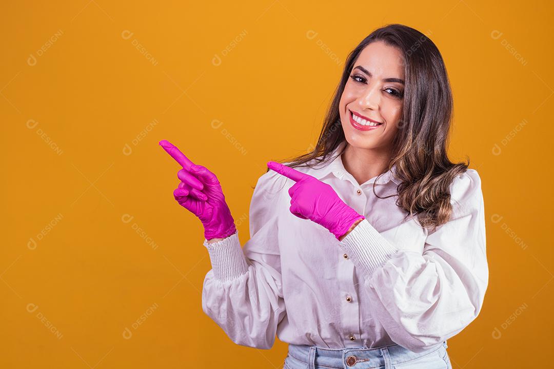 Mulher com luvas cor de rosa apontando para o lado. Conceito de promoção de beleza