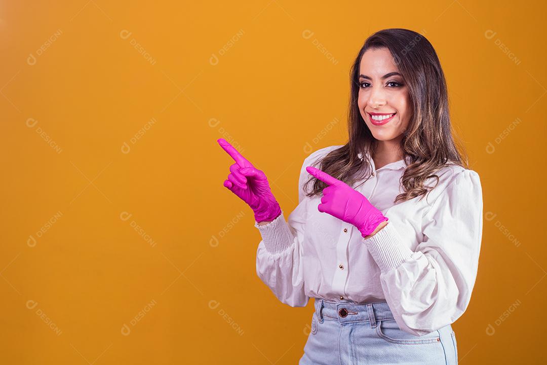 Mulher com luvas cor de rosa apontando para o lado. Conceito de promoção de beleza