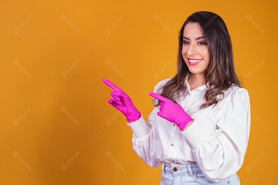 Mulher com luvas cor de rosa apontando para o lado. Conceito de promoção de beleza