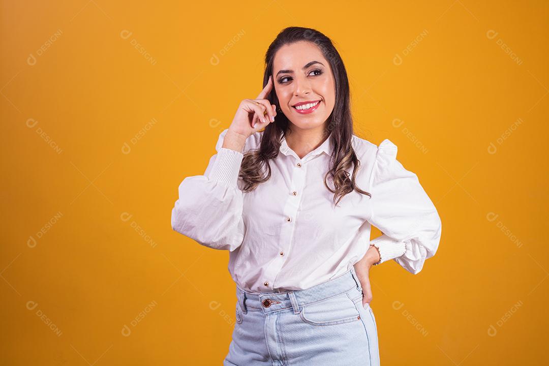 Mulher jovem e bonita de pé sobre fundo amarelo pensando em questão, expressão pensativa