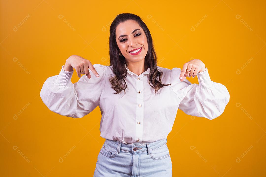 Olha, anuncie abaixo! jovem apontando para baixo lugar para ideia de negócio, olhando para a câmera com um sorriso. Tiro de estúdio interior isolado em fundo amarelo.
