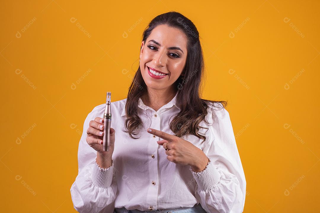 Nurse and beautician holding a dermapen for lip hydration on yellow background.