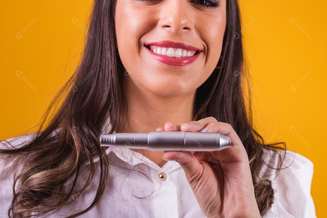 Enfermeira e esteticista segurando um dermapen para hidratação labial em fundo amarelo.