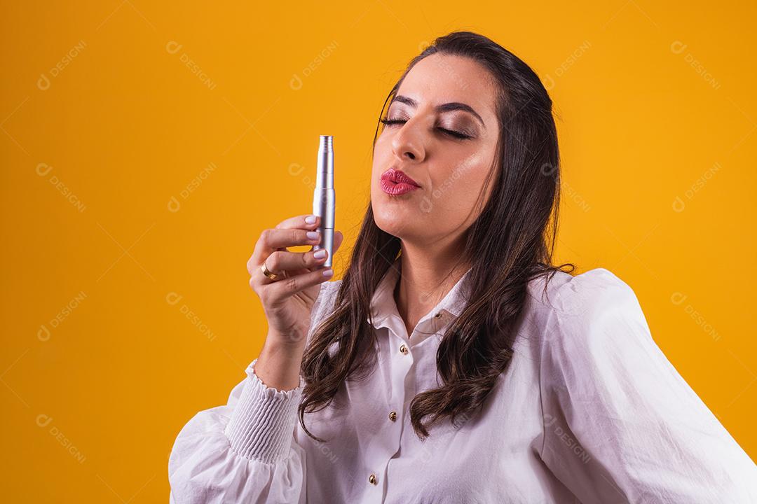 enfermeira e esteticista segurando um dermapen para hidratação labial em fundo amarelo franzindo os lábios