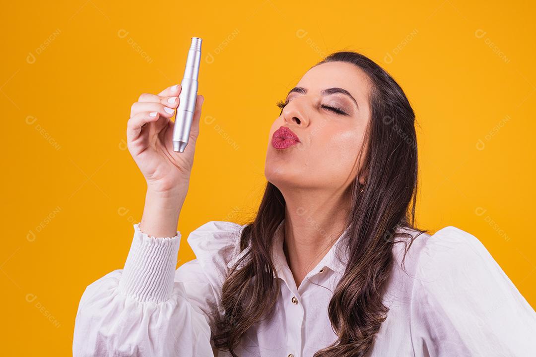 enfermeira e esteticista segurando um dermapen para hidratação labial em fundo amarelo franzindo os lábios