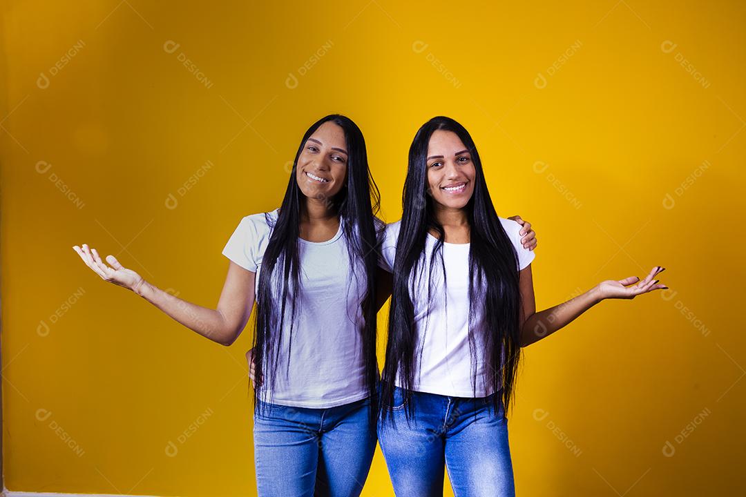 irmãs gêmeas idênticas apontando para baixo com camiseta branca
