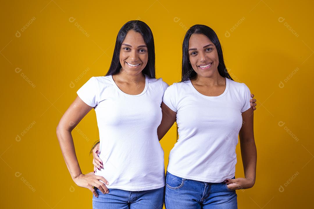 irmãs gêmeas fofas abraçando olhando para a câmera sorrindo