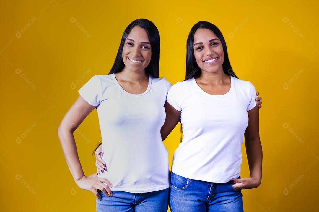 irmãs gêmeas idênticas apontando para baixo com camiseta branca