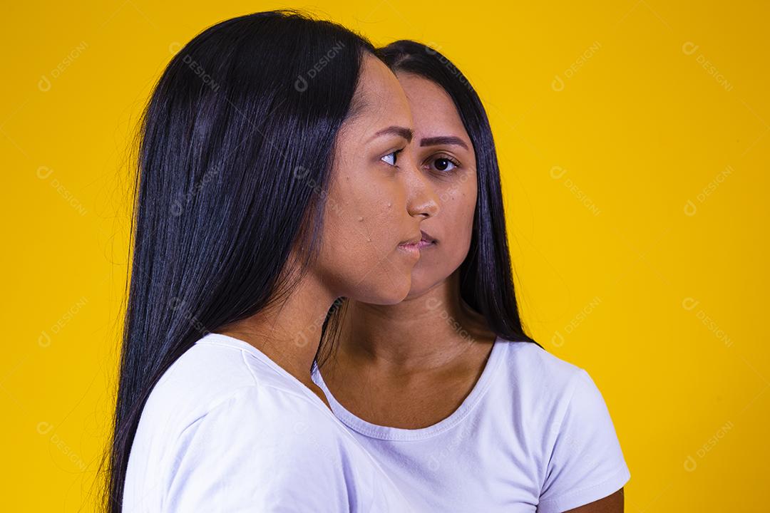 irmãs gêmeas idênticas em fundo amarelo mostrando metade do rosto um do outro. conceito de publicidade de gêmeos