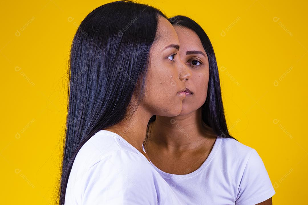 irmãs gêmeas idênticas em fundo amarelo mostrando metade do rosto um do outro. conceito de publicidade de gêmeos