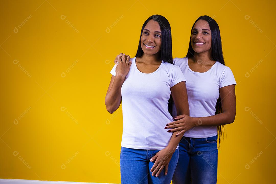 Irmãs gêmeas fofas abraçando olhando para a câmera sorrindo