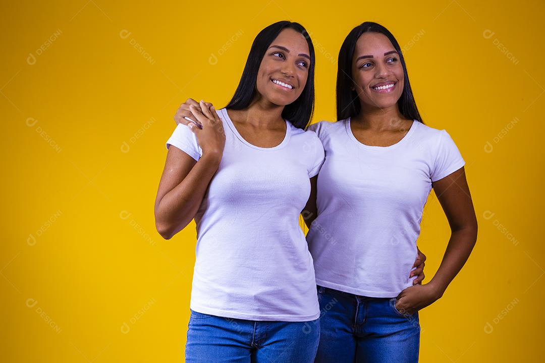 Irmãs gêmeas fofas abraçando olhando para a câmera sorrindo