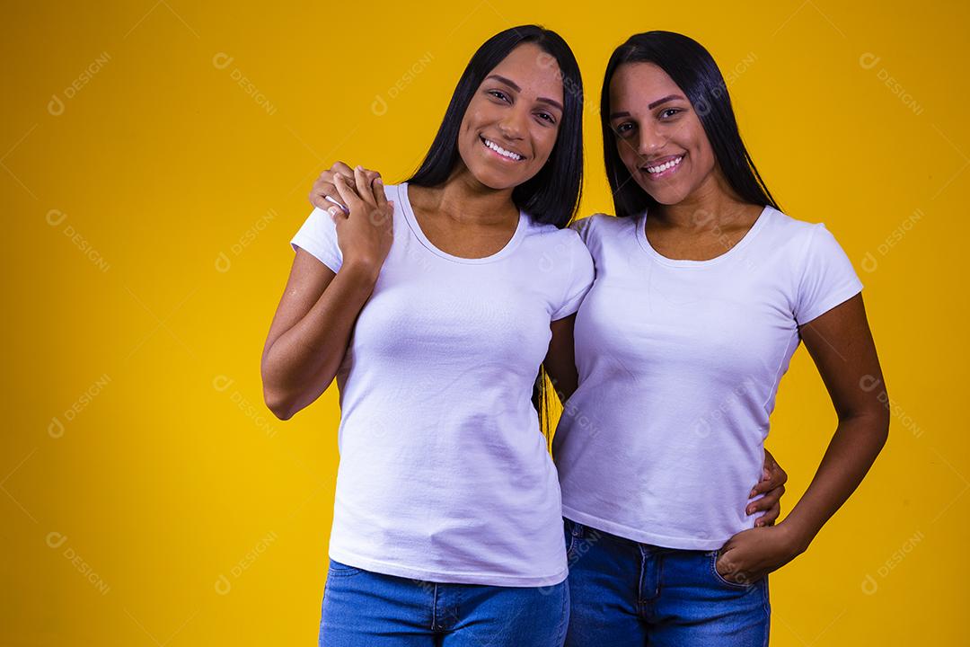 Irmãs gêmeas fofas abraçando olhando para a câmera sorrindo