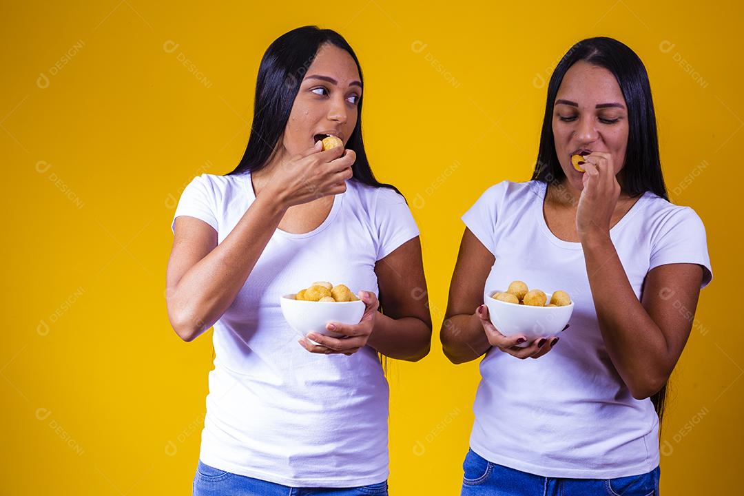 irmãs gêmeas comendo mini salgadinhos fritos