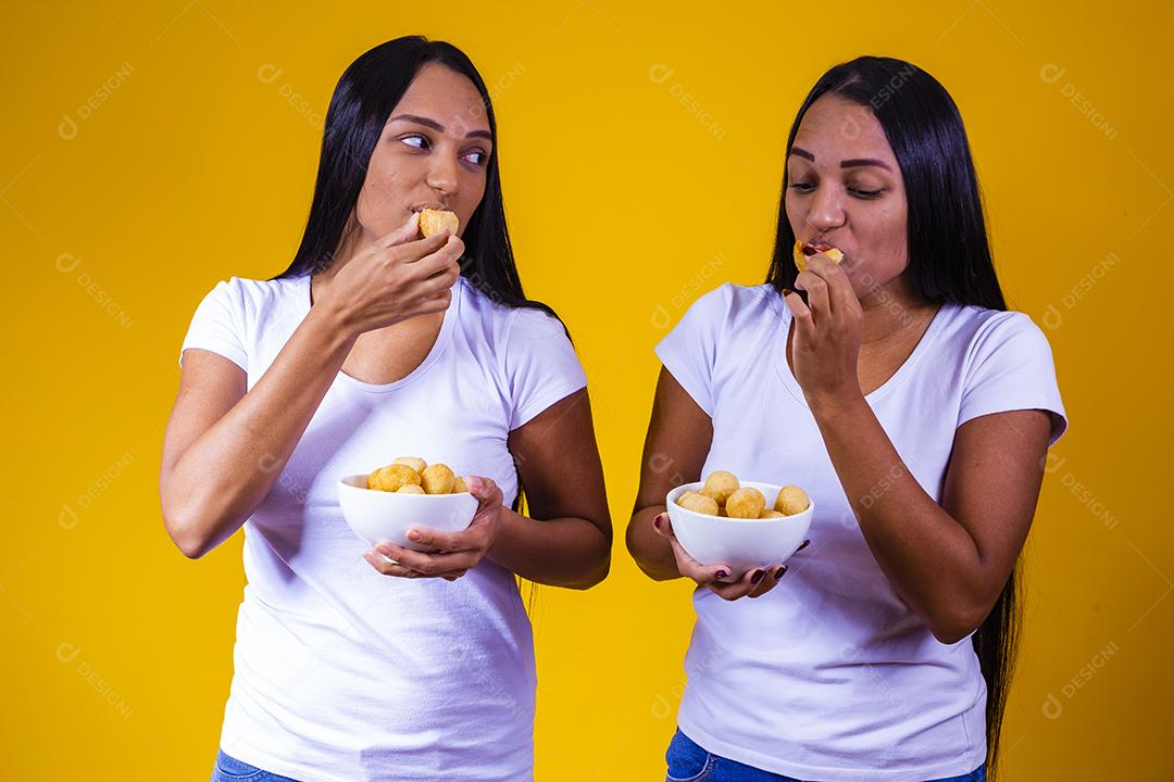 irmãs gêmeas comendo mini salgadinhos fritos