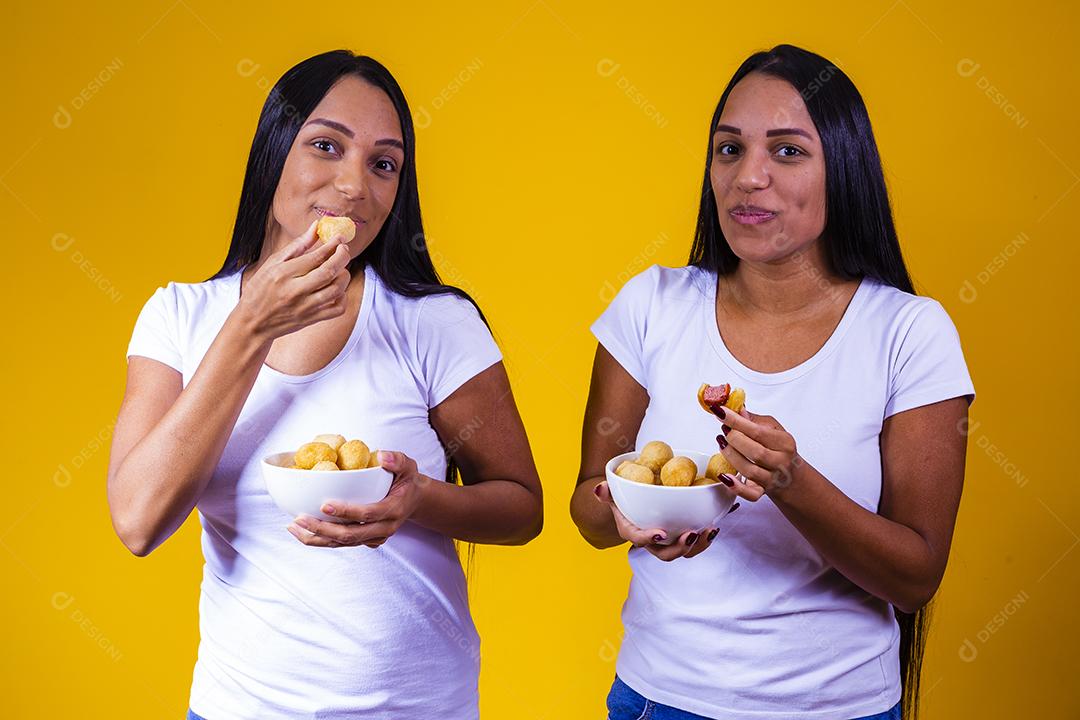 irmãs gêmeas comendo mini salgadinhos fritos