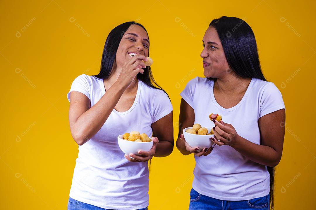 irmãs gêmeas comendo mini salgadinhos fritos