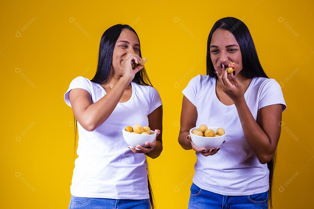 irmãs gêmeas comendo mini salgadinhos fritos