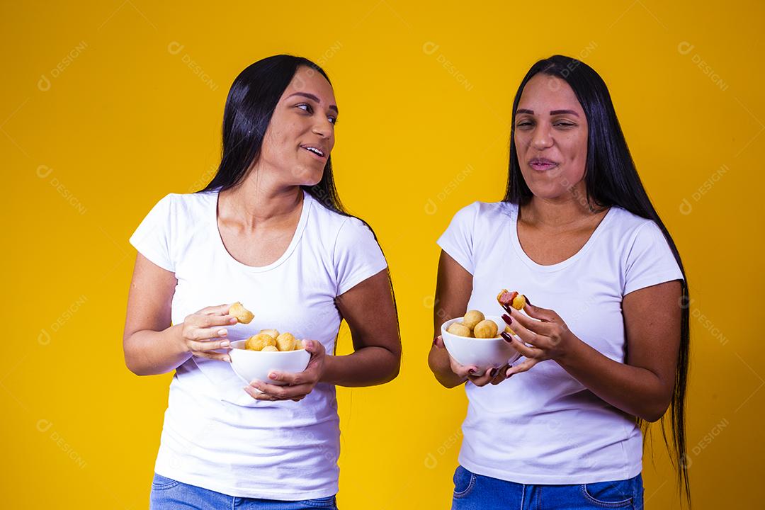 irmãs gêmeas comendo mini salgadinhos fritos