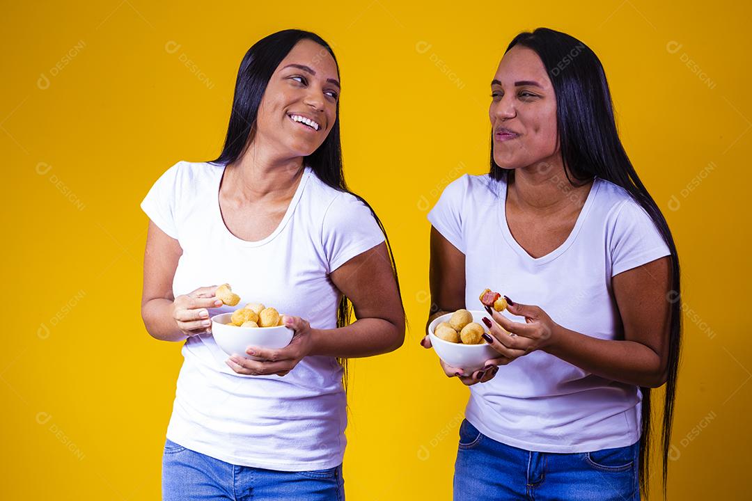 irmãs gêmeas comendo mini salgadinhos fritos