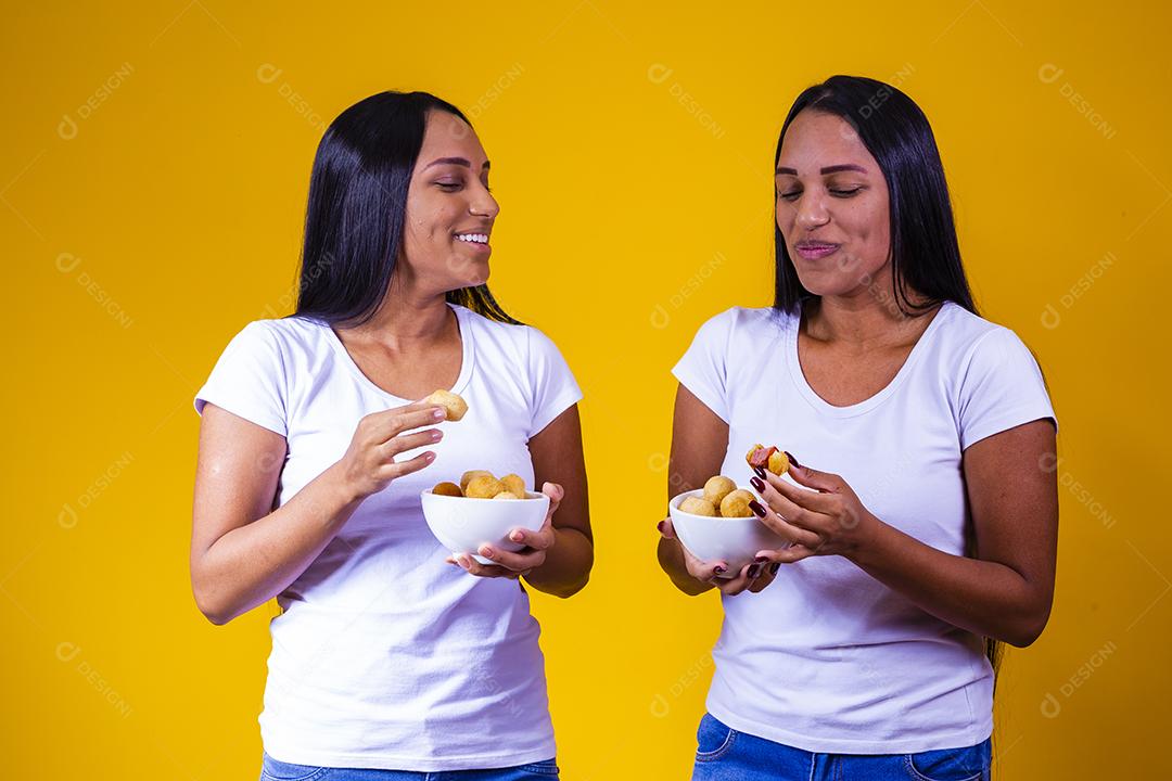 irmãs gêmeas comendo mini salgadinhos fritos