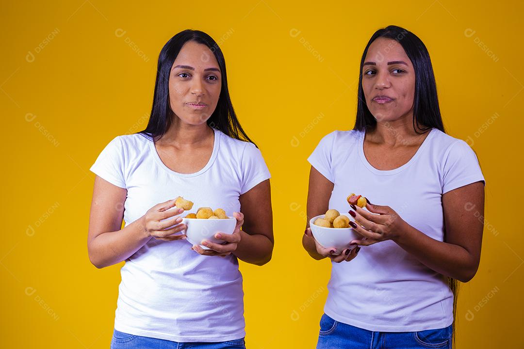 irmãs gêmeas comendo mini salgadinhos fritos