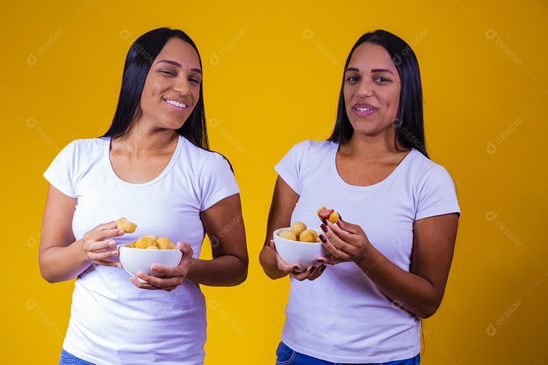 irmãs gêmeas comendo mini salgadinhos fritos