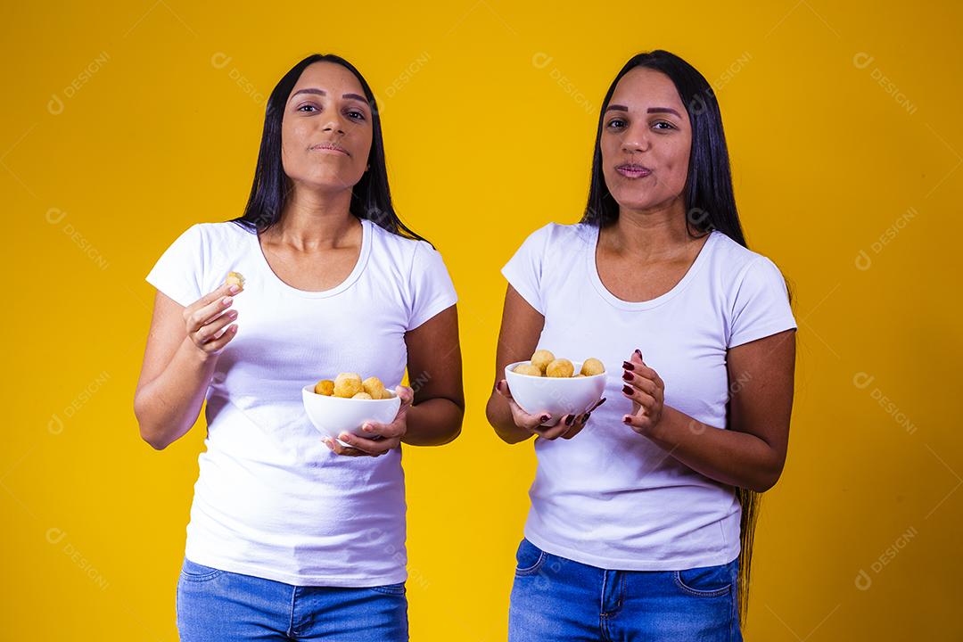 irmãs gêmeas comendo mini salgadinhos fritos