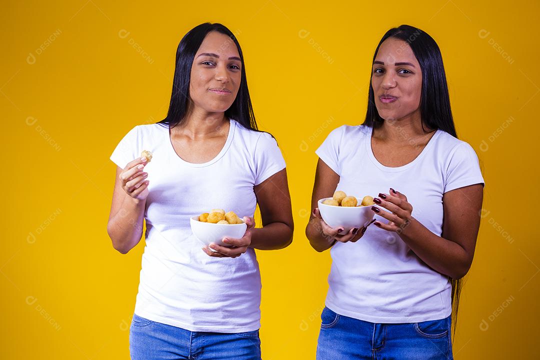 irmãs gêmeas comendo mini salgadinhos fritos