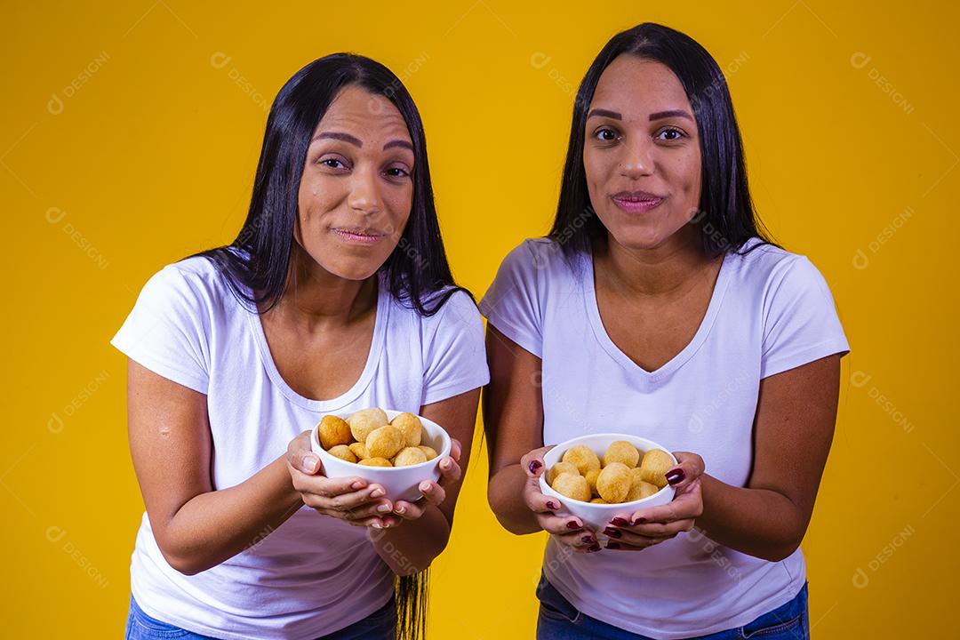 irmãs gêmeas comendo mini salgadinhos fritos