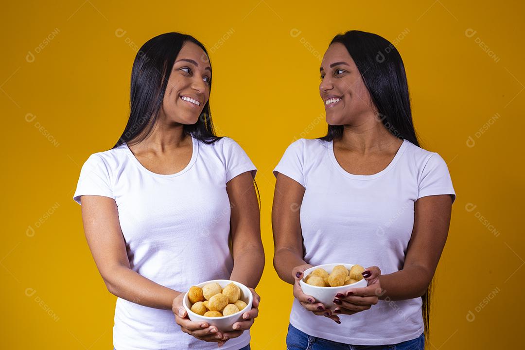 irmãs gêmeas comendo mini salgadinhos fritos