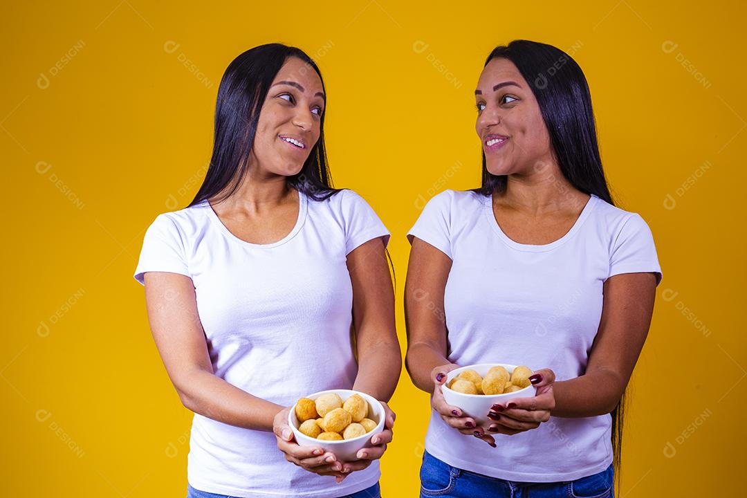 irmãs gêmeas comendo mini salgadinhos fritos