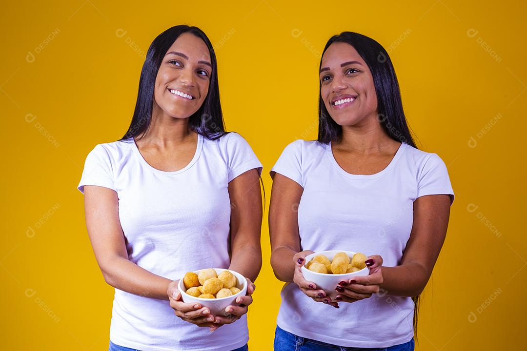 irmãs gêmeas comendo mini salgadinhos fritos