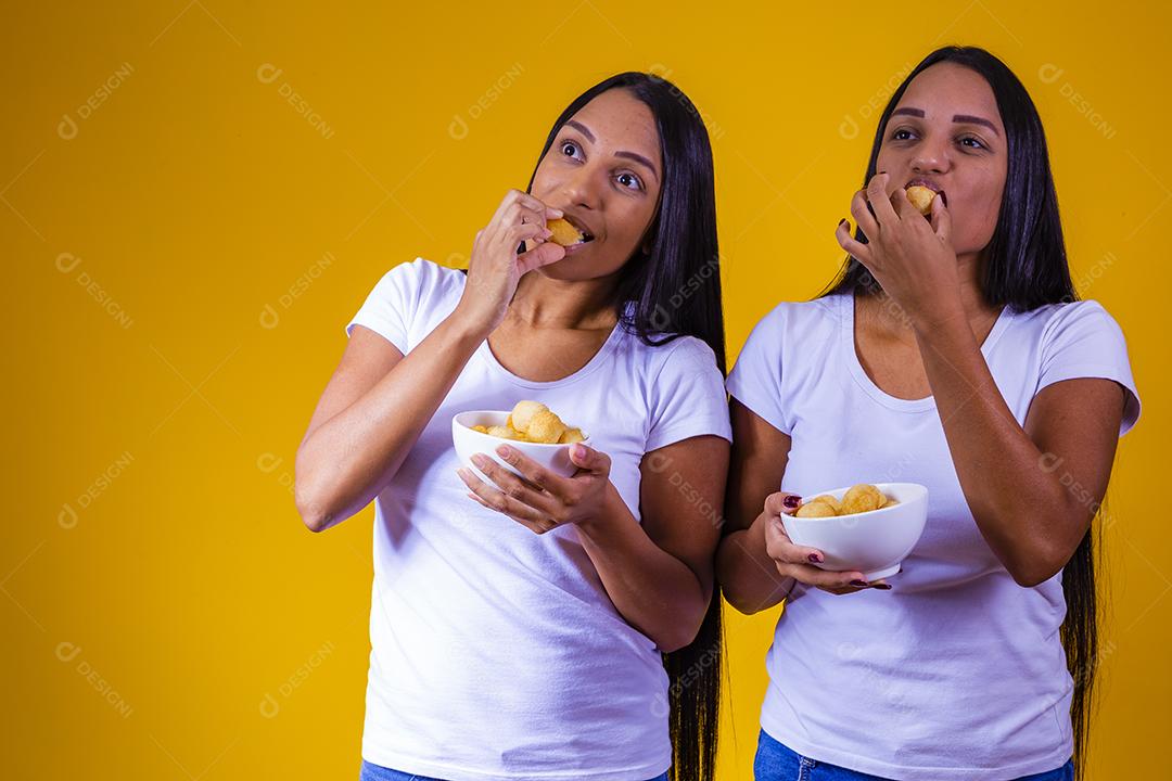 irmãs gêmeas comendo mini salgadinhos fritos