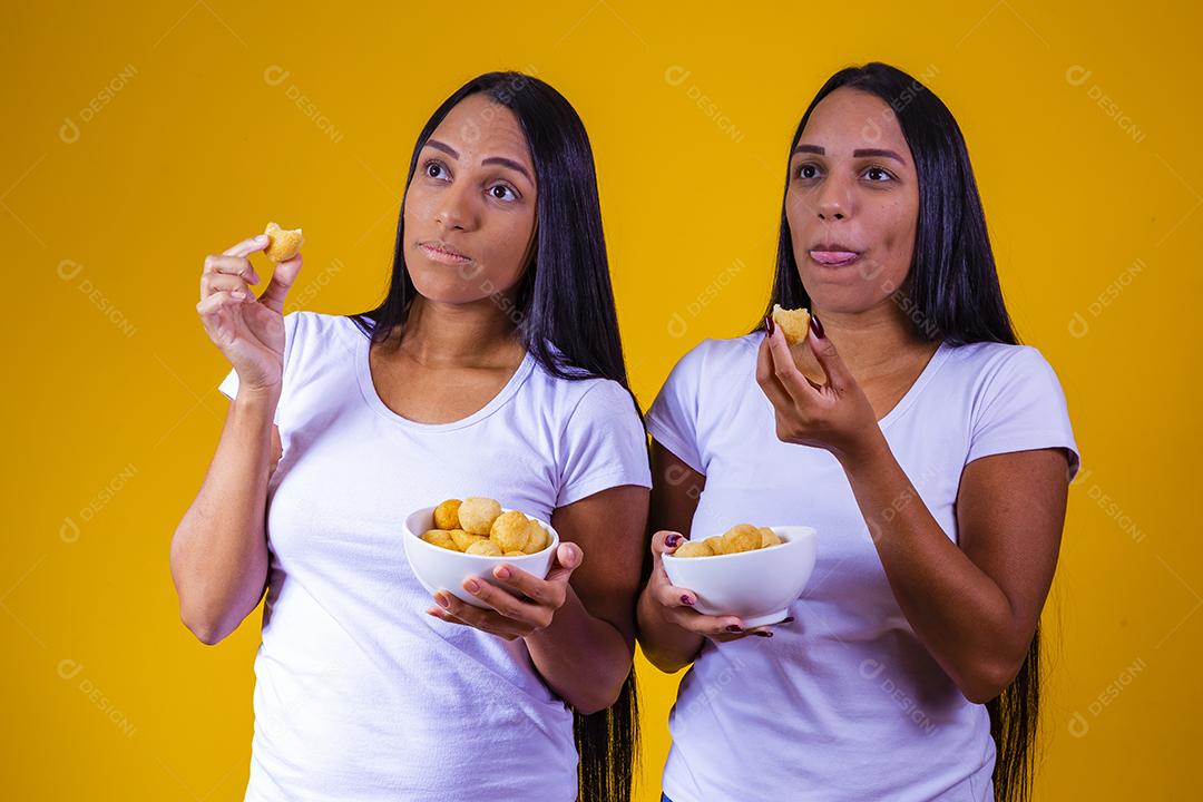 irmãs gêmeas comendo mini salgadinhos fritos