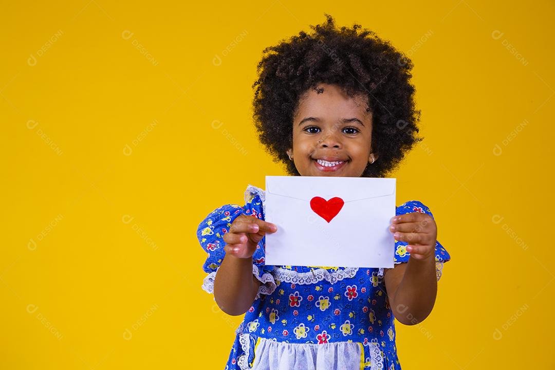 Festa Junina no Brasil, adorável garotinha afro segurando uma carta de amor no festival brasileiro de junho vestindo fantasia.