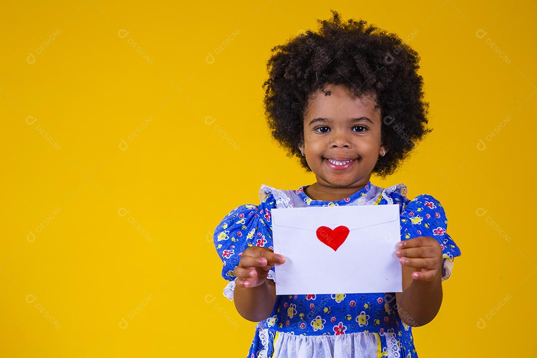 Festa Junina no Brasil, adorável garotinha afro segurando uma carta de amor no festival brasileiro de junho vestindo fantasia.