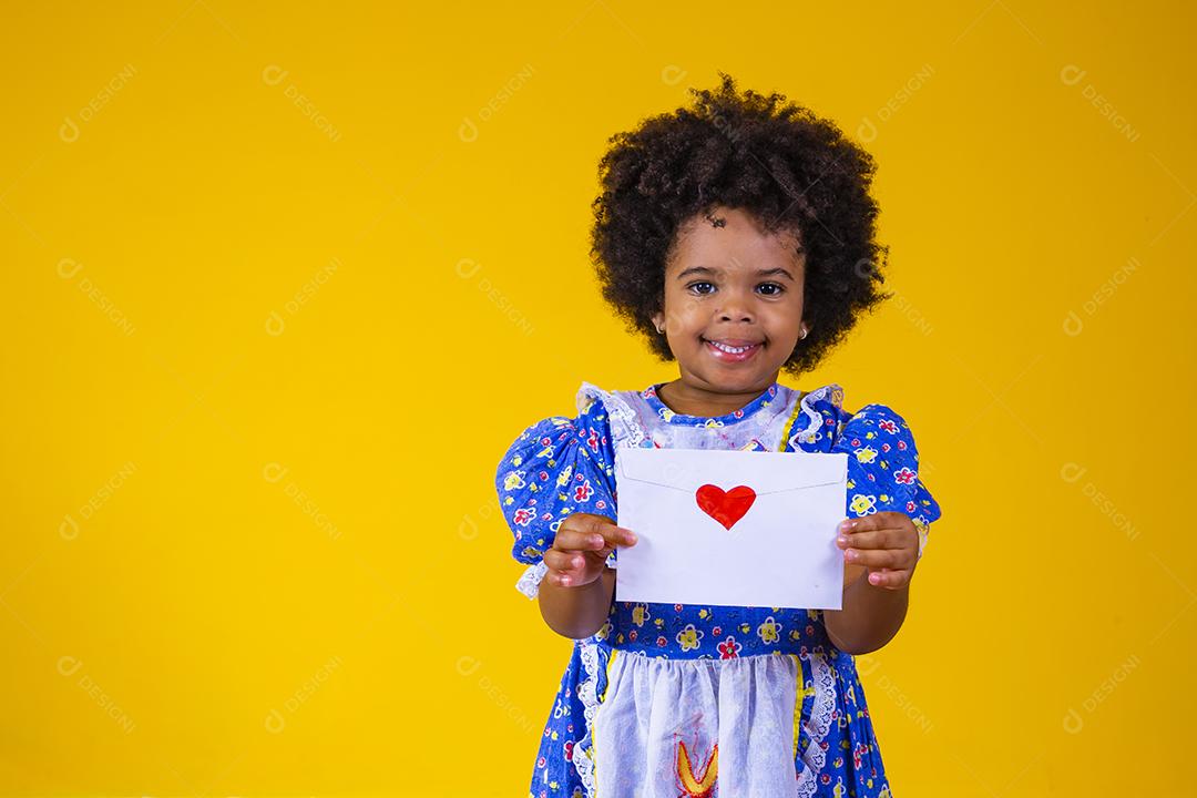 Festa Junina no Brasil, adorável garotinha afro segurando uma carta de amor no festival brasileiro de junho vestindo fantasia.