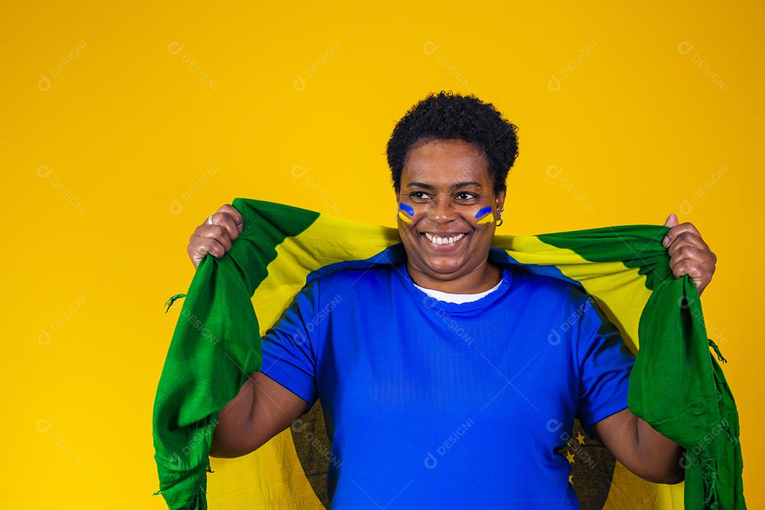 torcedor brasileiro. Fã de mulher brasileira comemorando no futebol ou partida de futebol em fundo amarelo. Cores do Brasil.