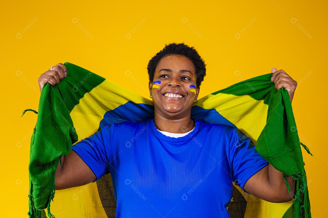 torcedor brasileiro. Fã de mulher brasileira comemorando no futebol ou partida de futebol em fundo amarelo. Cores do Brasil.