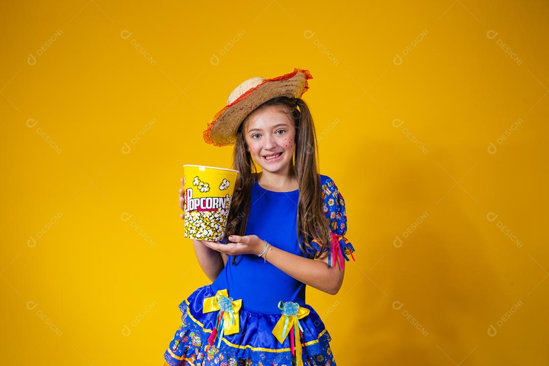 Menina caucasiana bonitinha com roupa típica de festa junina comendo