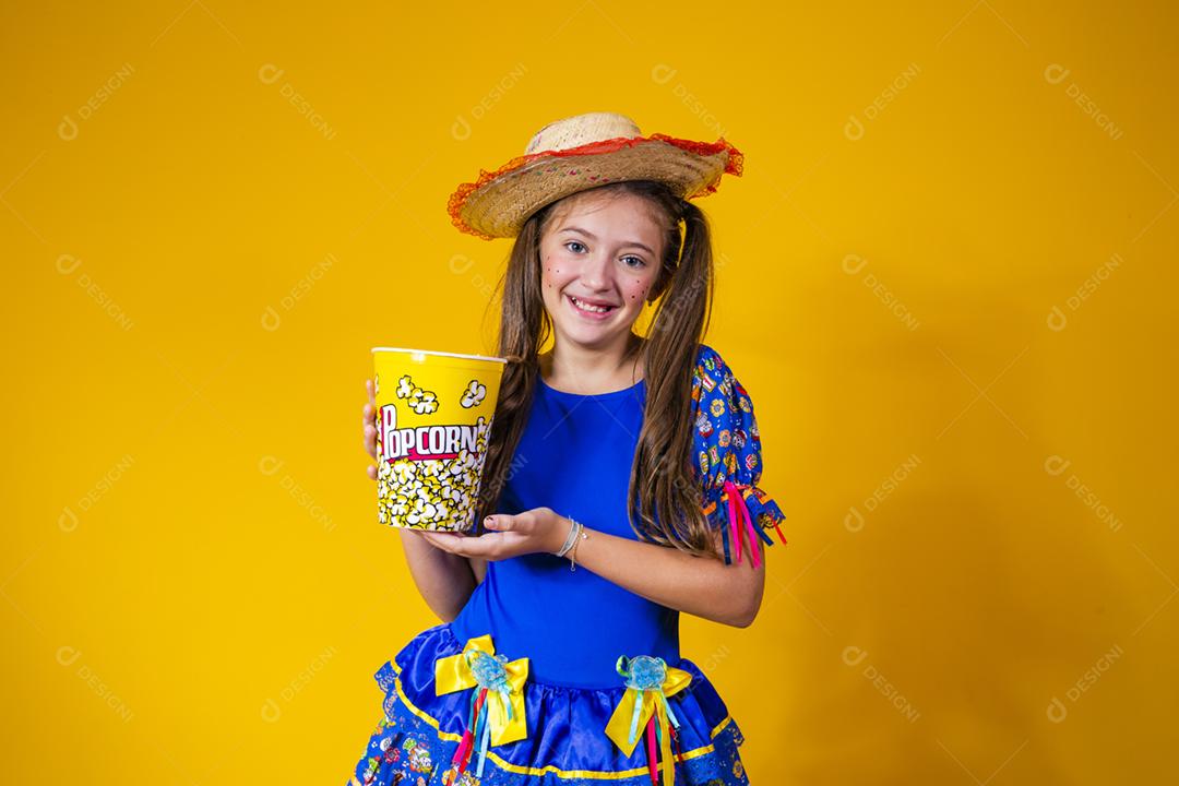 Menina caucasiana bonitinha com roupa típica de festa junina comendo