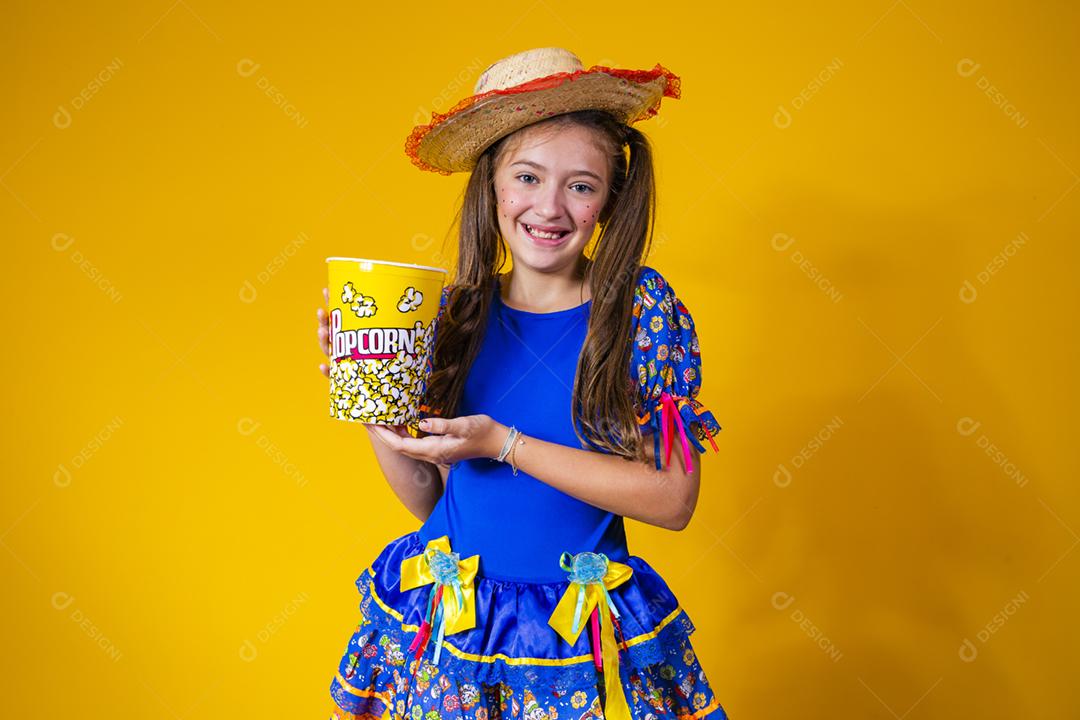 Menina caucasiana bonitinha com roupa típica de festa junina comendo