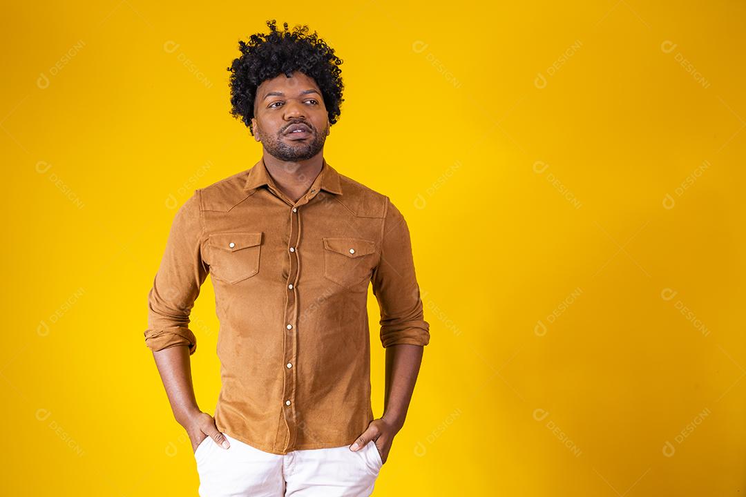 Retrato de bonitão africano sorrindo olhando para a câmera sobre parede amarela. Estudante confiante ou jovem empresário.