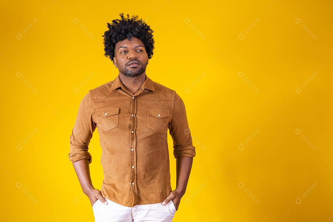 Retrato de bonitão africano sorrindo olhando para a câmera sobre parede amarela. Estudante confiante ou jovem empresário.