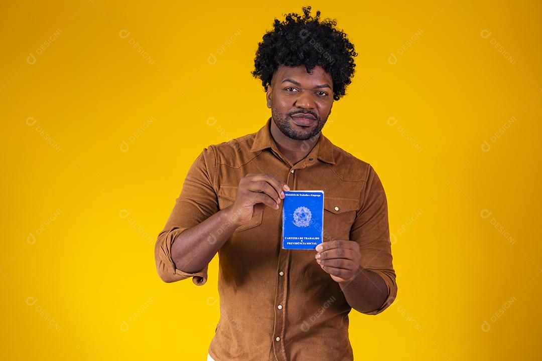 Homem afro brasileiro com trabalho documental e segurança social, (Carteira de Trabalho e Previdência Social) em fundo amarelo