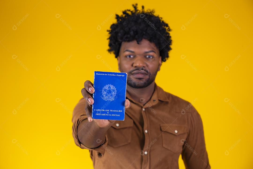 Homem afro brasileiro com trabalho documental e segurança social, (Carteira de Trabalho e Previdência Social) em fundo amarelo