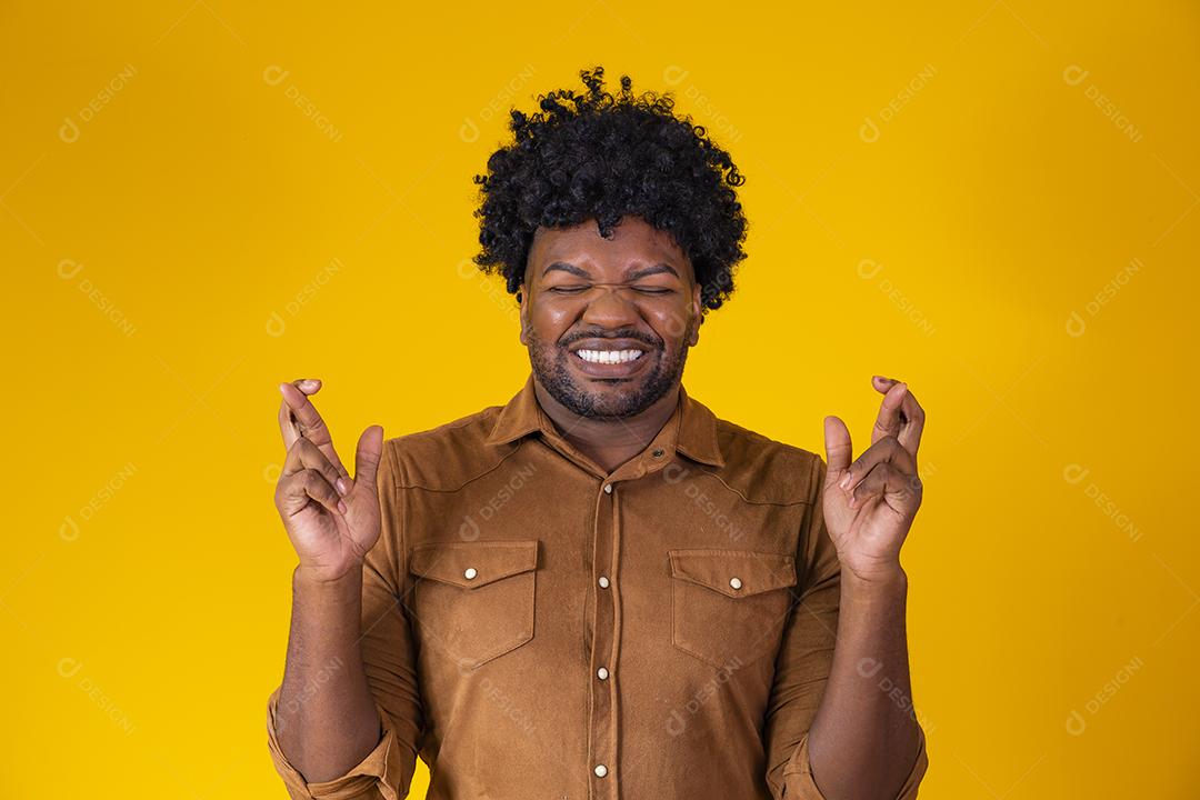 Jovem negro com os dedos cruzados desejando sorte
